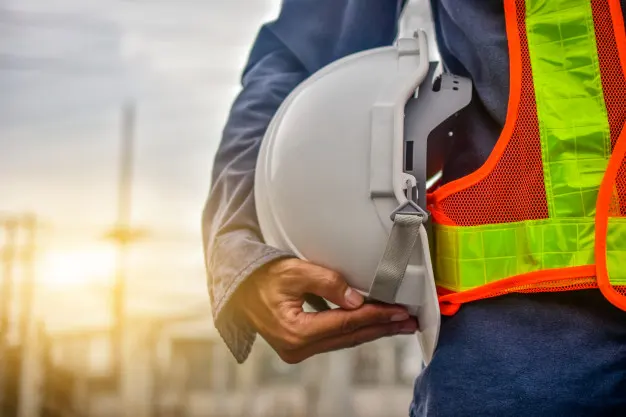 Inspection professional holding a hard hat at an industrial worksite